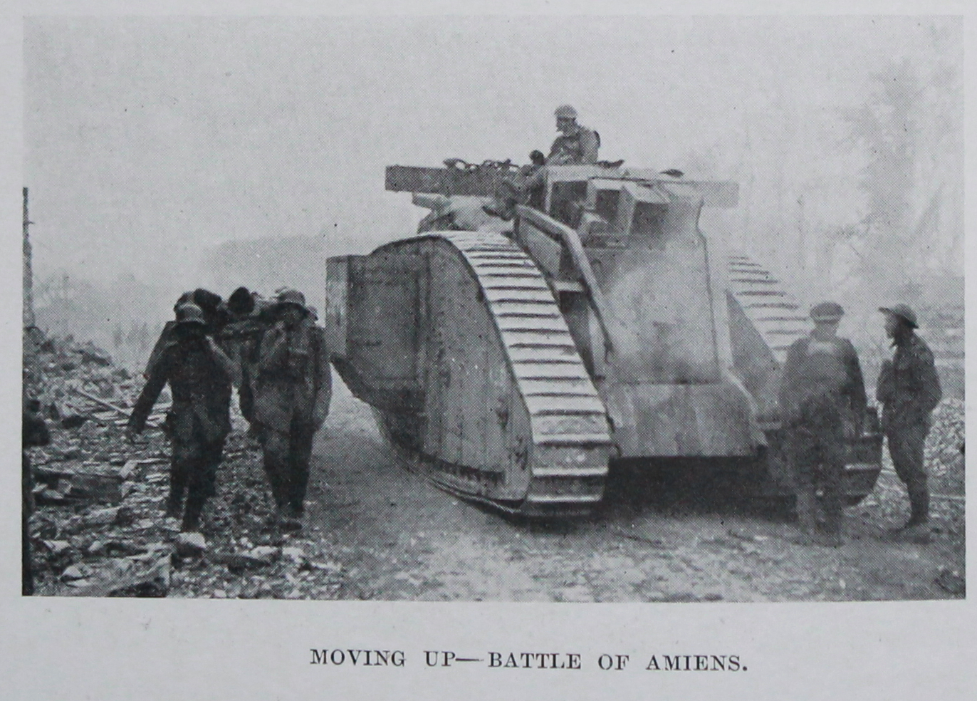 British tank moving up in the Battle of Amiens. German prisoners on the left carry a casualty to the rear on a stretcher. From The Tank Corps by Major Clough Williams-Ellis and A. Williams-Ellis.