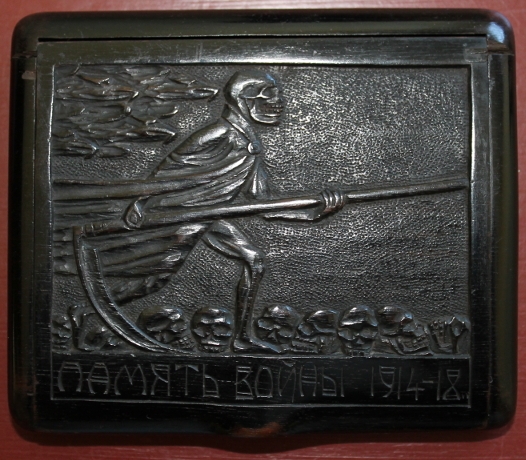 Wooden cigarette box carved by Г. САВИНСКИ (?; G. Savinskiy), a Russian POW. The Grim Reaper strides across a field of skulls on the cover. The base includes an intricate carving of the years of war years, '1914' and, turning it 90 degrees, '1918.'
Text:
ПДМЯТЬ ВОИНЬ 1914-18
To memory of soldiers 1914-18
Reverse:
1914
1918
Г. САВИНСКИ (?)
G. Savinskaya
