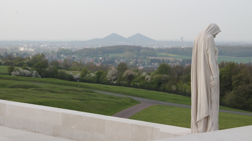 Detail from the Canadian Memorial at Vimy Ridge: the figure of Canada Bereft, or Mother Canada, looking down at a casket below her, mourns her dead. In the distance are the slag heaps of Lens and the Douai Plain.